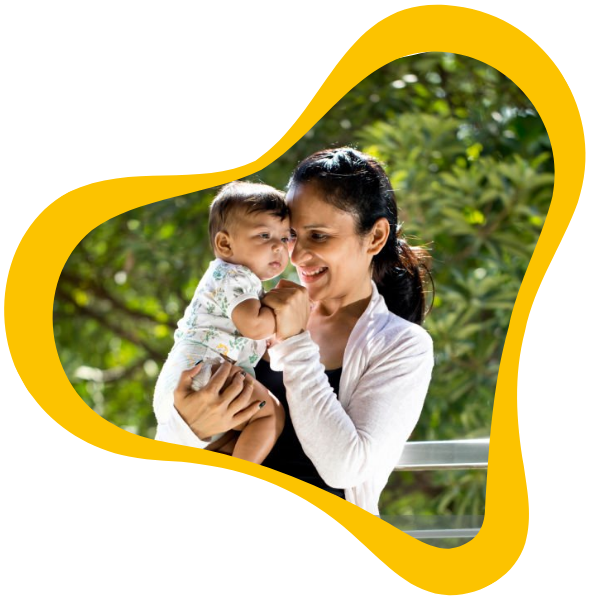 lady holding a baby in front of a tree